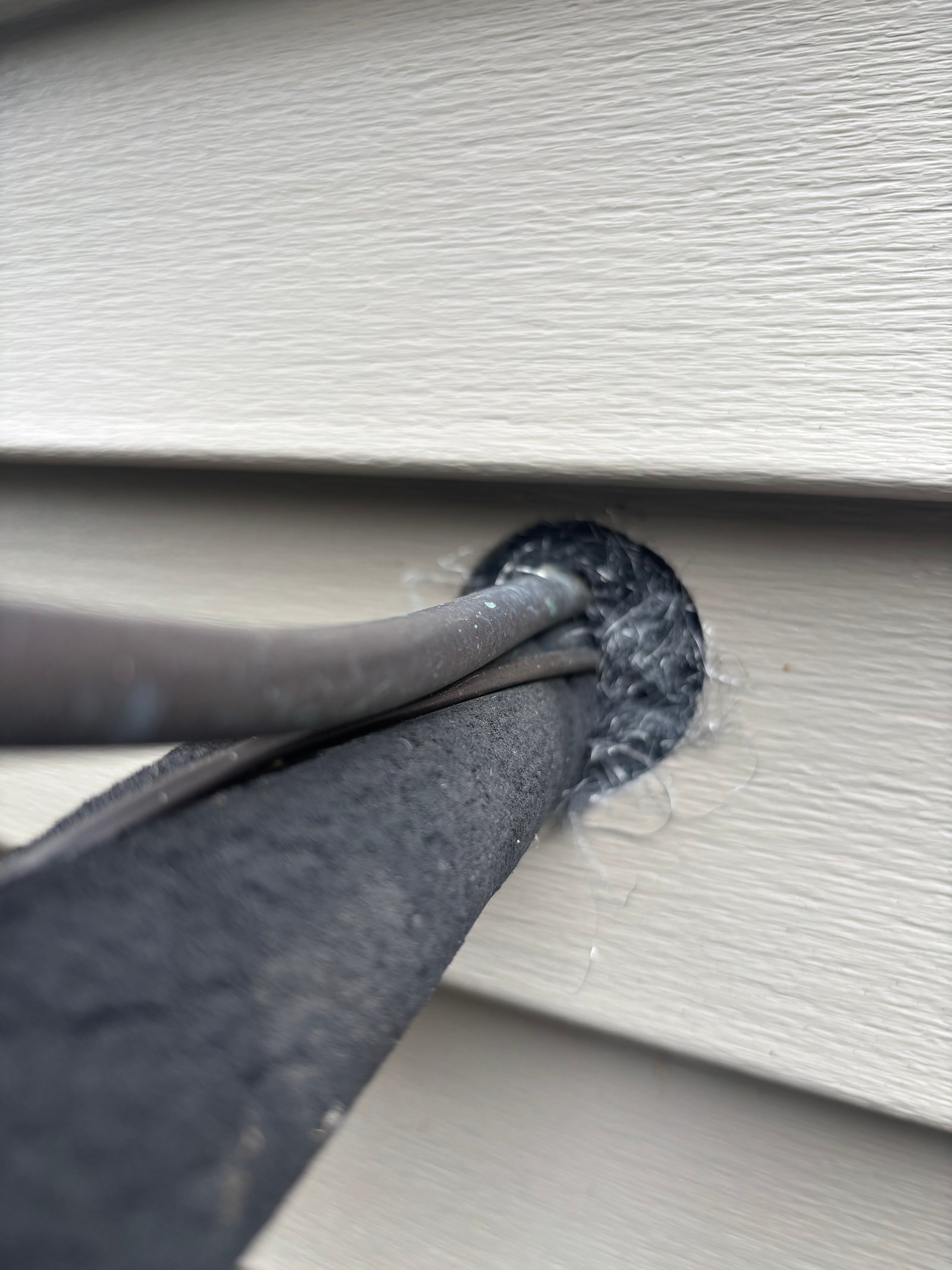The same A/C line penetration packed tight with Excluder fill, closing the gap around the conduit