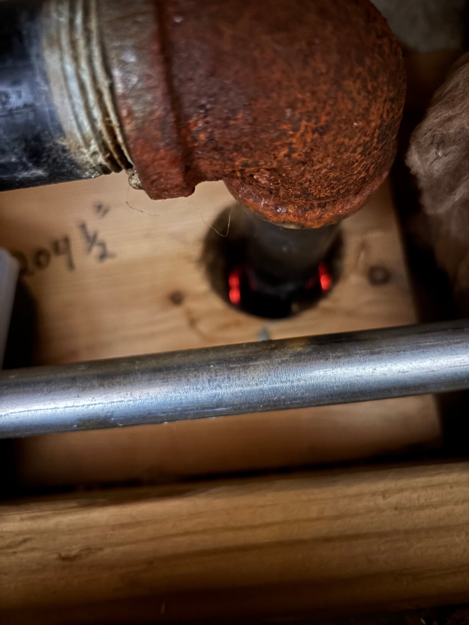 A gas line penetration through the rim joist with daylight visible through the open gap around the pipe