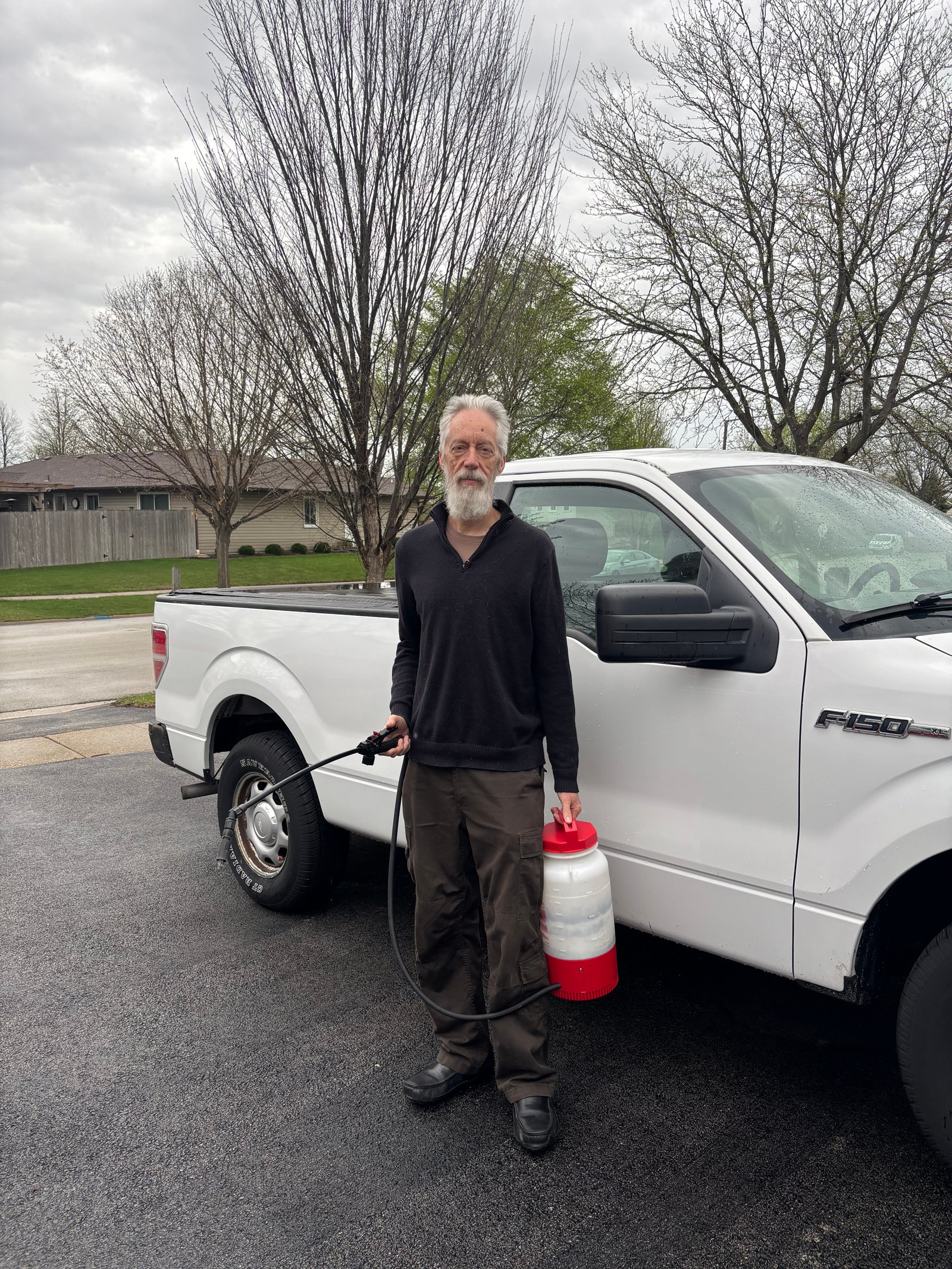 Patrick, owner of Sanctuary Pest Control, standing with his service truck and sprayer